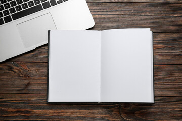 Blank book with laptop on wooden background
