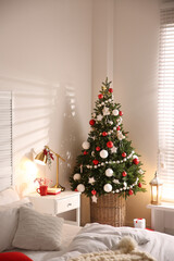 Beautiful decorated Christmas tree in bedroom interior