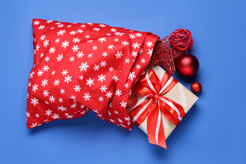 Santa Claus bag with Christmas gift on color background