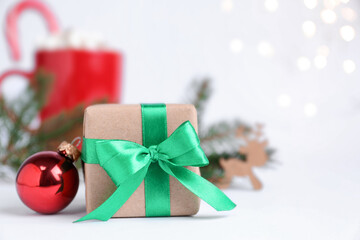 Gift box and Christmas ball on blurred background, closeup. Space for text