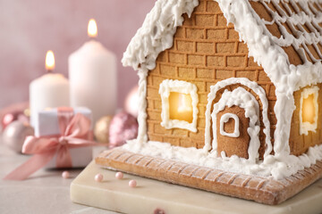 Beautiful gingerbread house decorated with icing on light table, closeup