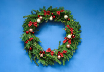 Fototapeta na wymiar Beautiful Christmas wreath with festive decor on blue background, top view