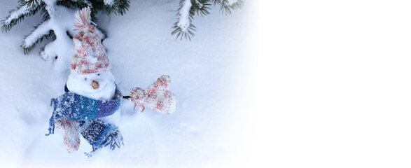 cheerful snowman in a knitted hat, scarf and mittens in a snowdrift under a Christmas tree. good...