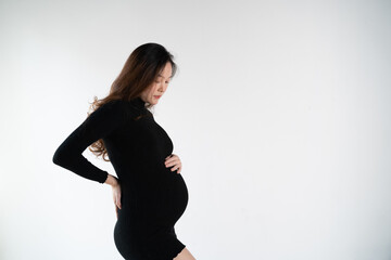portrait of 8 months pregnant Asian woman in white studio room, Woman touching her abdomen belly with care on white background. pregnancy fashion set.