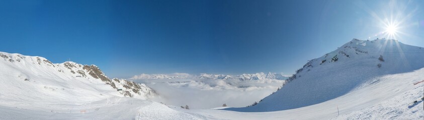 Fototapeta na wymiar Aerial View above the clouds. Rosa Khutor Ski Resort, mountains covered by snow in Krasnaya Polyana, Russia.