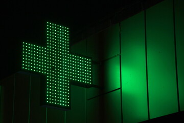 Glowing pixel cross of LED lamps on black background.