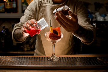 barman add ingredients to glass with small pumpkin and pepper inside