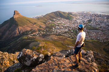 A fit trail runner looking down on Cape Town from the top of the mountain with a view of the city and the ocean. - 397565929