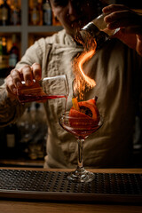 bartender gently add ingredients to glass with vegetables inside and makes fire over it