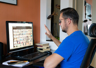 Man with glasses is talking on a video chat on a computer, conference calls at home.