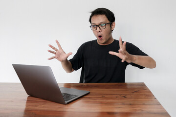 Wow face of Young Asian man shocked what he see in the laptop when working isolated grey background