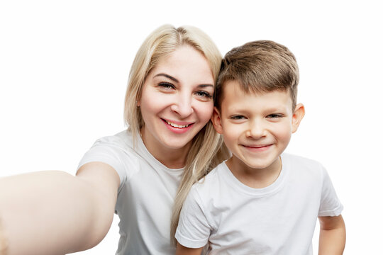 Young blonde mom with her son 7 years old make a selfie. Love and tenderness. Isolated on white background.