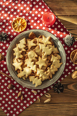 A plate of delicious homemade holiday shaped cookies on a red tablecloth on a wooden table. Concept of creating a cozy atmosphere and festive mood. Top view