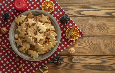 Plate of delicious homemade holiday shaped cookies on a red tablecloth on a wooden table. Concept of creating a cozy atmosphere and festive mood. Top view and copy space