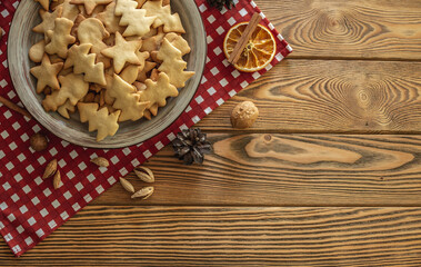 Plate of delicious homemade holiday shaped cookies on a red tablecloth on a wooden table. Concept of creating a cozy atmosphere and festive mood. Top view and copy space