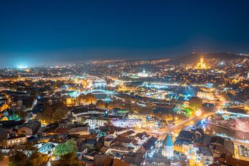 Fototapeta na wymiar Tbilisi, Georgia. Elevated Rooftop View Of Famous Landmarks In Night Illuminations. Georgian Capital Skyline Cityscape