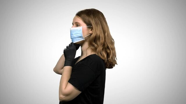 Woman demonstrating the use of a surgical mask: Putting on, coughing and sneezing, using gloves. Medium shot over white background.