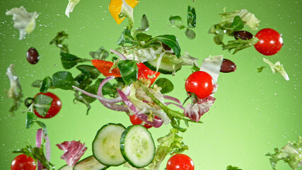 Flying vegetable salad isolated on green background. Healthy eating and lifestyle.