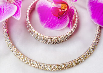 Bracelet and necklace on white fabric and purple Orchid
