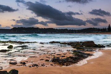 Grey clouds and rocky foreground overcast sunrise at the beach