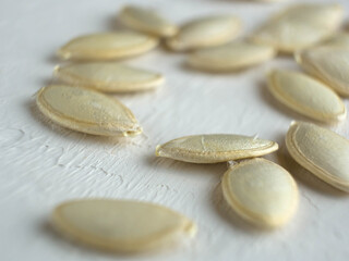 Pumpkin seeds scattered on the white table.