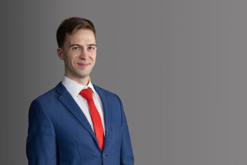 handsome, attractive man in blue suit and red tie on grey background. confident, serious businessman, lawyer, manageer looking at the camera and smiling. business concept. text