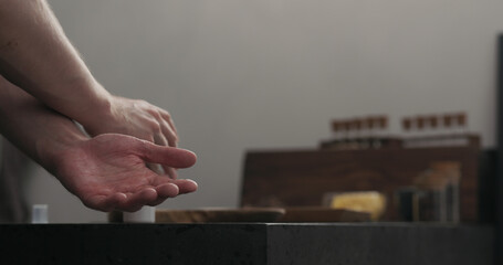 man spraying sanitizer on his hands on kitchen