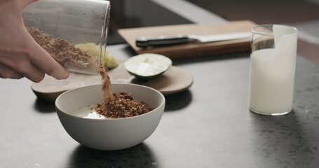 man making granola with mango in white bowl on kitchen