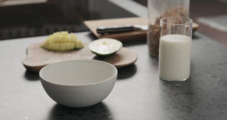 making granola with mango in white bowl on kitchen