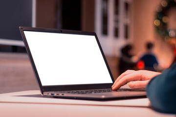 Close-up laptop mockup with white screen. A male freelancer works in a cafe.