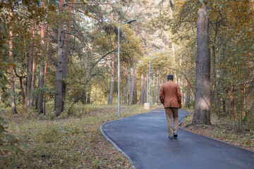 a man walking on an asphalt path in a forest park