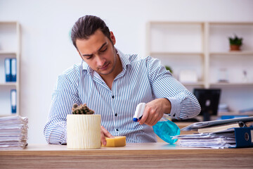 Young male employee cleaning office during pandemic