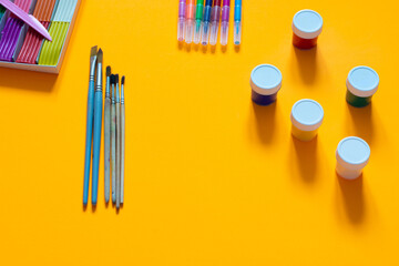 Stationery, plasticine, brushes, gouache and felt-tip pens lie on an orange background