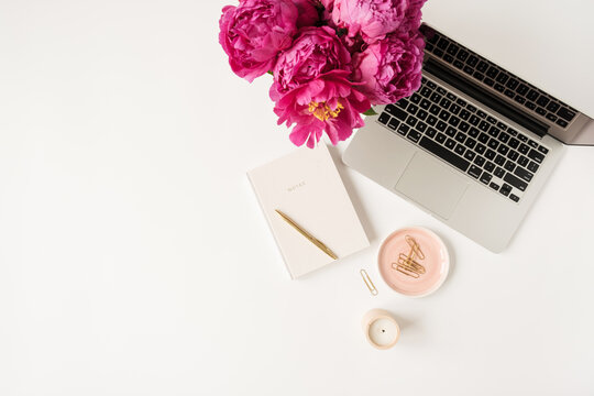 Laptop, Beautiful Pink Peony Tulip Flowers Bouquet And Notebook On White Table Background. Flat Lay, Top View Minimalist Home Office Desk Workspace.