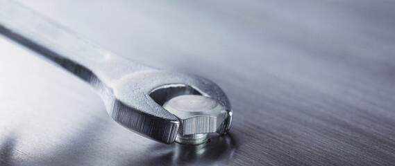 Wrench tightens bolt in steel billet. Spanner, bolt, screw and nuts.