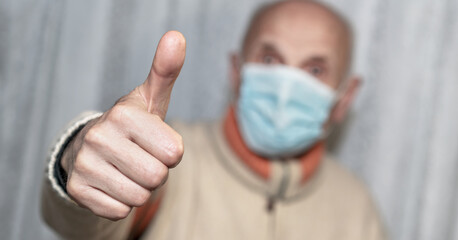 Old caucasian blurred man wearing mask giving thumbs up