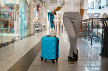 Woman with suitcase poses at the showcase in mall