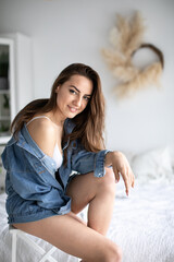 Fototapeta premium Smiling young woman relaxing at home. Brunette female wearing casual clothing and looking at camera.