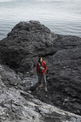 The girl makes her way through the rocky coast of the Black Sea. Novy Svet, Crimea. Clear Sunny day. Hiking, traveling, Freedom, Lifestyle concept.