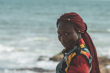 African woman with rasta hair with attached small ghana flags on the Accra coast Ghana
