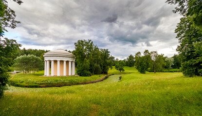 Fototapeta na wymiar Summer landscape in a city Park with trees, pavilion, river, sky with clouds