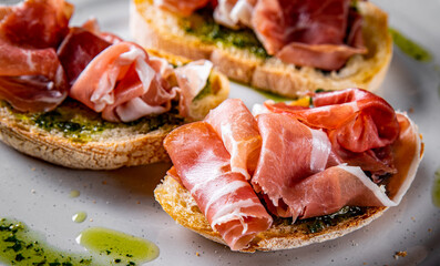 Bruschetta with prosciutto and pesto sauce on plate