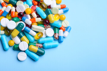 Close-up shot of numerous colorful capsules and pills on blue background. Medicine, healthcare, copy space.