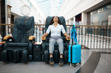 Girl with suitcase relax in massage chair, airport