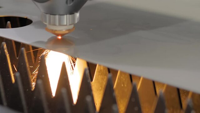 Automatic cnc laser cutting machine working with sheet metal with sparks at factory, plant - close up. Metalworking, machining, industrial, equipment, technology, manufacturing concept