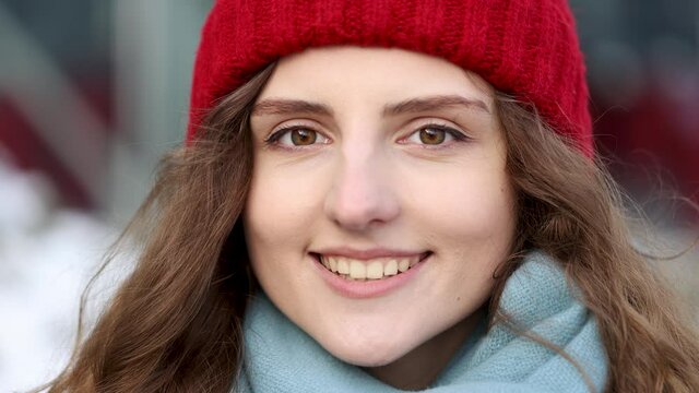 Outdoor portrait of attractive urban young woman in stylish winter outfit and red hat smiling to camera. Beautiful charming girl enjoying fashion. Slow motion 4k.