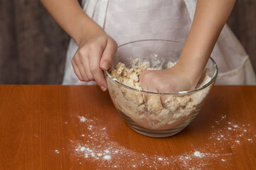 Obraz na płótnie Canvas A girl in a chef's apron kneads cookie dough. Homemade baking.