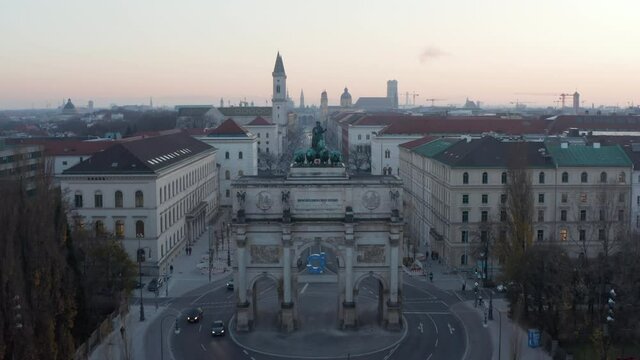 Siegestor in Munich, Germany in Beautiful Sunset Dusk scenic Cityscape with University in background, Aerial Dolly in towards 