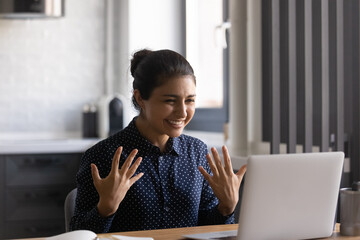 Friendly young indian female teacher sit by laptop webcam explain pupils students new learning material on distance. Confident hindu lady coach provide online training via video conference webinar