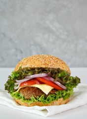 tasty cheeseburger with lettuce, tomatoes, red onions on a white background